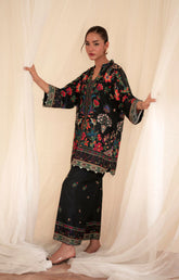 Woman wearing a floral embroidered outfit standing between white curtains