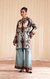 Woman wearing a patterned outfit with a floral and bird design against a plain background