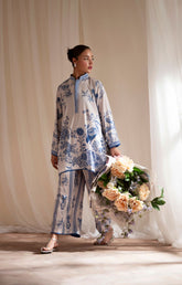 Woman in a floral outfit holding a bouquet of flowers against a neutral background