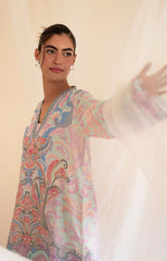 Woman wearing a colorful patterned kurta against a plain background