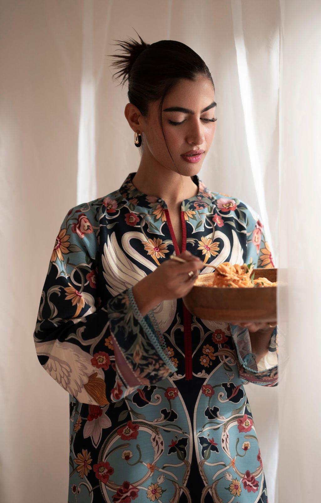 Woman in a colorful floral outfit holding a bowl of food.