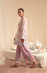 Woman wearing a floral outfit in a softly lit room with a couch and decorative items.