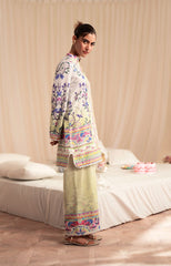 Woman in a colorful floral outfit standing in a bedroom.