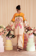 Woman in a colorful traditional outfit standing among floral arrangements on a wooden floor.