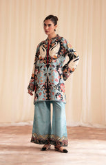 Woman wearing a patterned outfit with a floral and bird design against a plain background