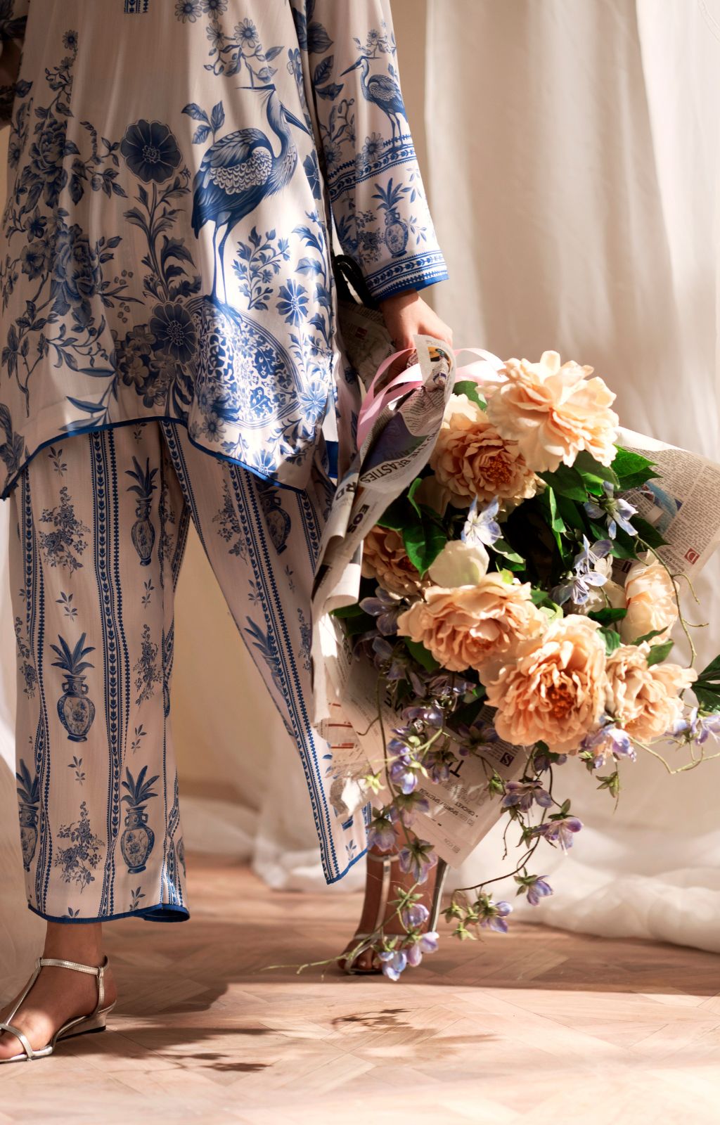 Person wearing a blue and white patterned outfit holding a bouquet of flowers.