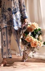 Person wearing a blue and white patterned outfit holding a bouquet of flowers.